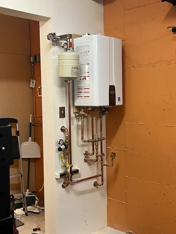 Plumbing technician inspecting water heater connections in Ponderosa Park